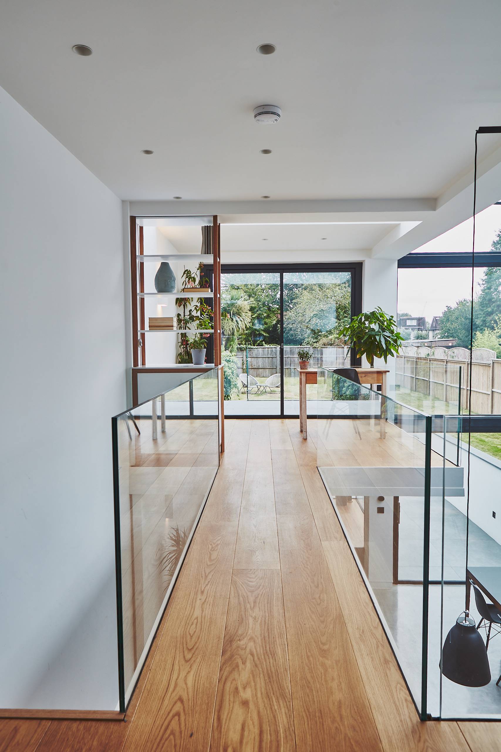 Upper-level glass walkway gallery bridge connecting light-filled floors in a modern extension, Love Locations TW1.