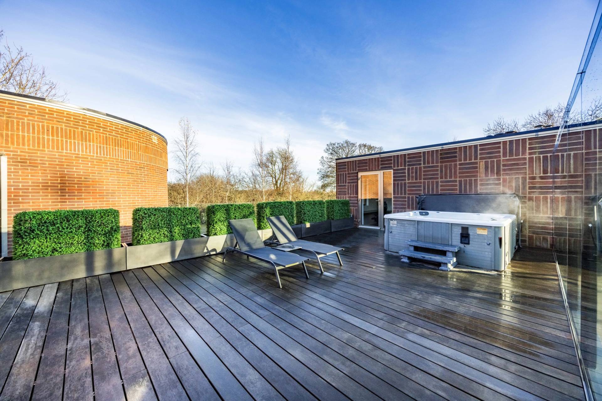 Private roof deck terrace featuring an outdoor hot tub and sun loungers overlooking greenery, Love Locations WD7.