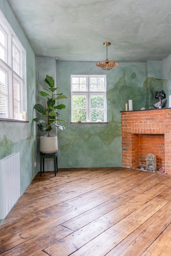 Character reception room with green textured walls, brick fireplace and timber floors at Love Locations in Liss, Hampshire GU33.