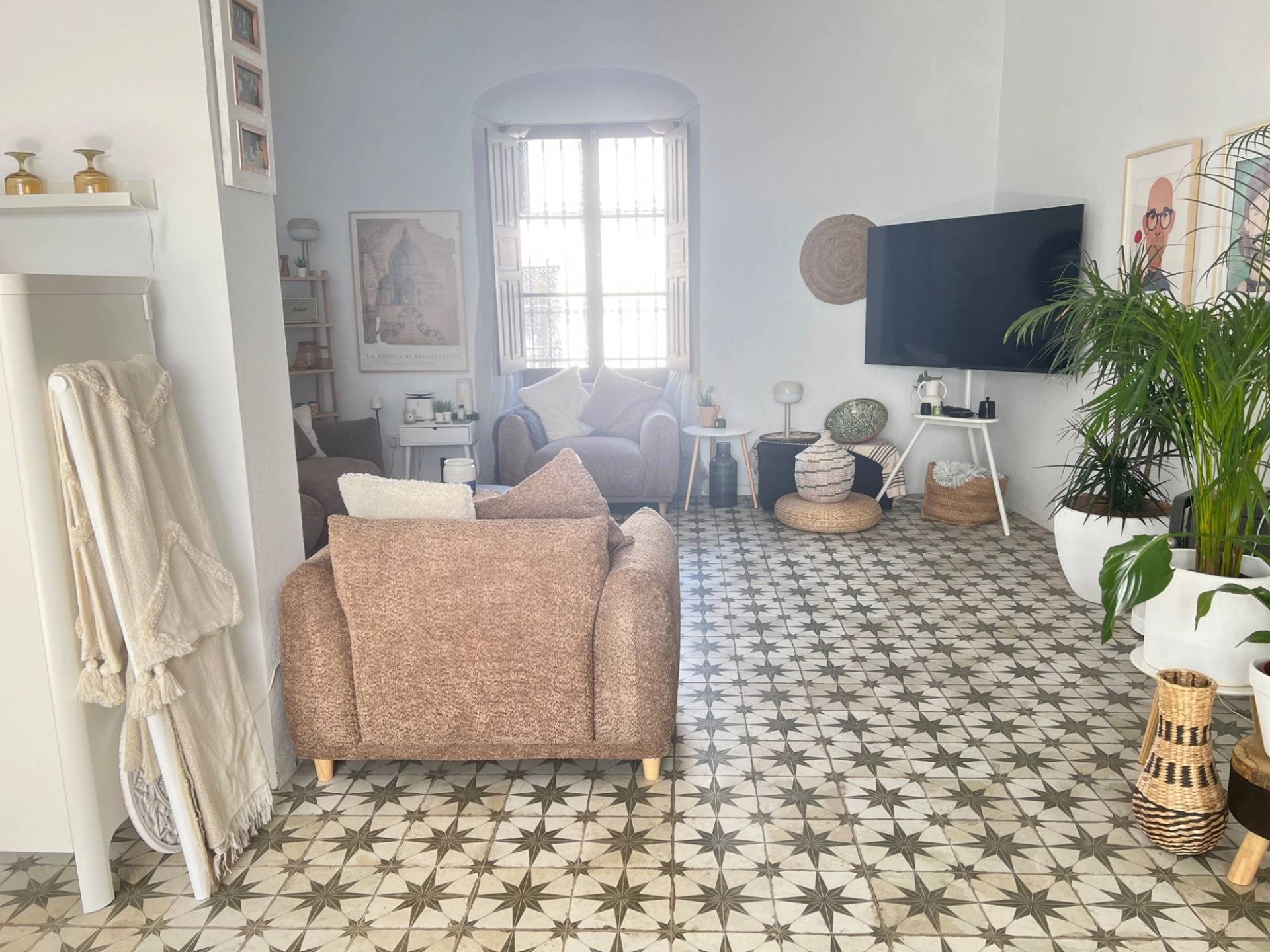 Cozy sitting room location house in Jimena de la Frontera via Love Locations, featuring plush brown armchairs, patterned mosaic floor tiling, and a large traditional window.
