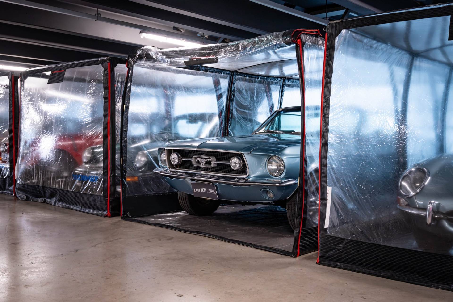 Classic blue Ford Mustang in a protective storage pod inside a Brentford car showroom through Love Locations.