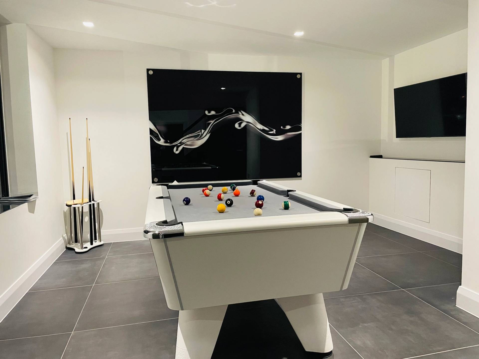Private games room featuring a modern white pool table with dark wall artwork and grey slate floor tiles in Loughton, perfect for lifestyle campaign filming, Love Locations IG10.