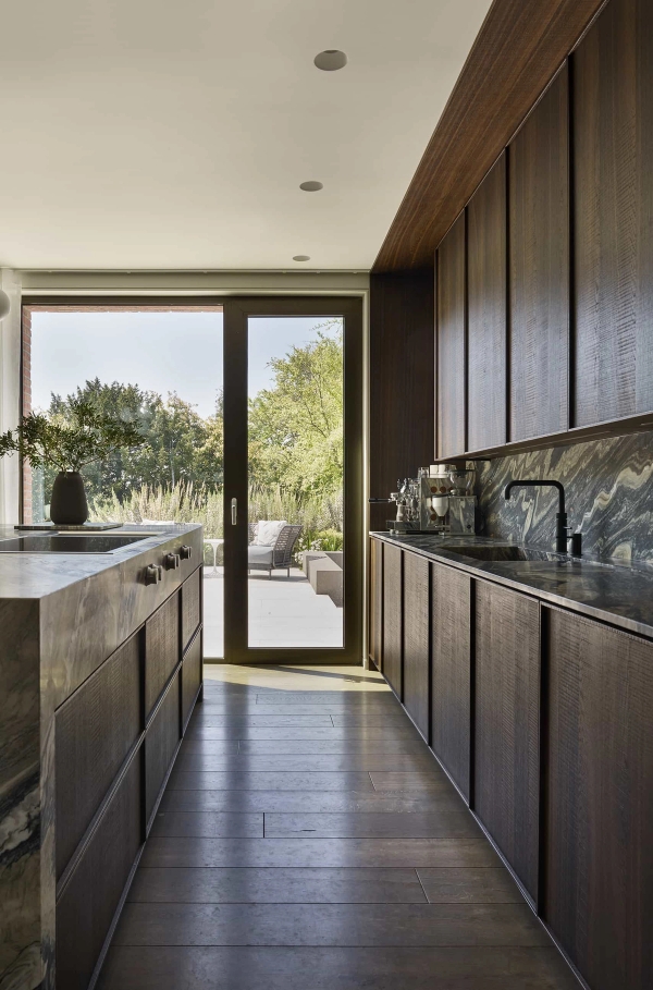 Modern kitchen with integrated dark wood units and sliding glass garden doors for lifestyle media hire, Love Locations.