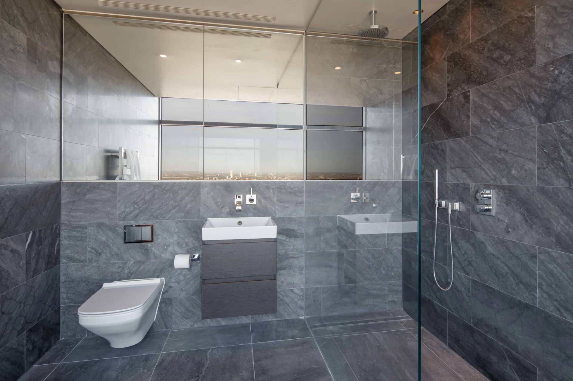Contemporary penthouse shower bathroom location in East London, EC2A near Liverpool Street Station featuring dark stone tiling, floating vanity basin, and high-rise views, the ultimate backdrop for luxury brand campaigns and commercial filming via Love Locations.