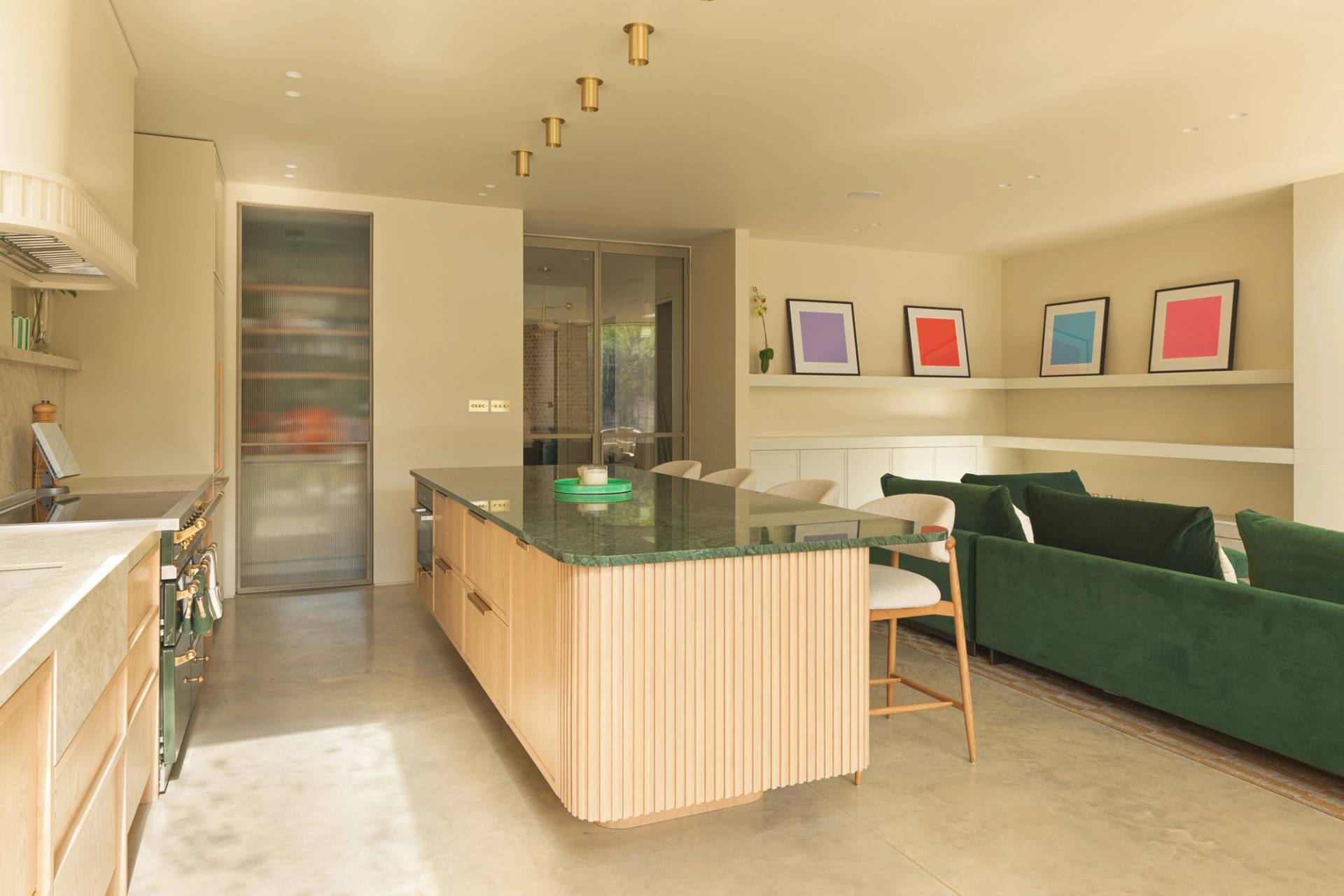 Open-plan kitchen island view looking toward the light-filled lounge area via Love Locations.