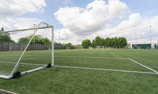 Love Locations outdoor sports pitch Reading South East London SE2: Green 3G artificial turf football field showing a white goalpost and crisp white lines, perfect for sportswear ads.