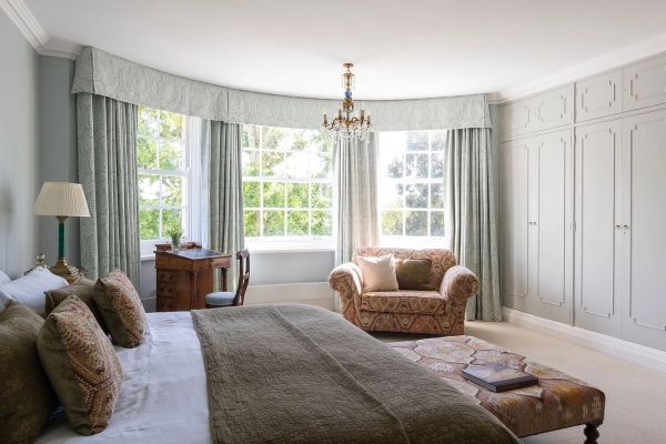 Love Locations luxury bedroom location BN44: Sprawling bedroom suite showing a curved bay window alcove with an armchair setup, tailored for calm lifestyle photography and film sets.