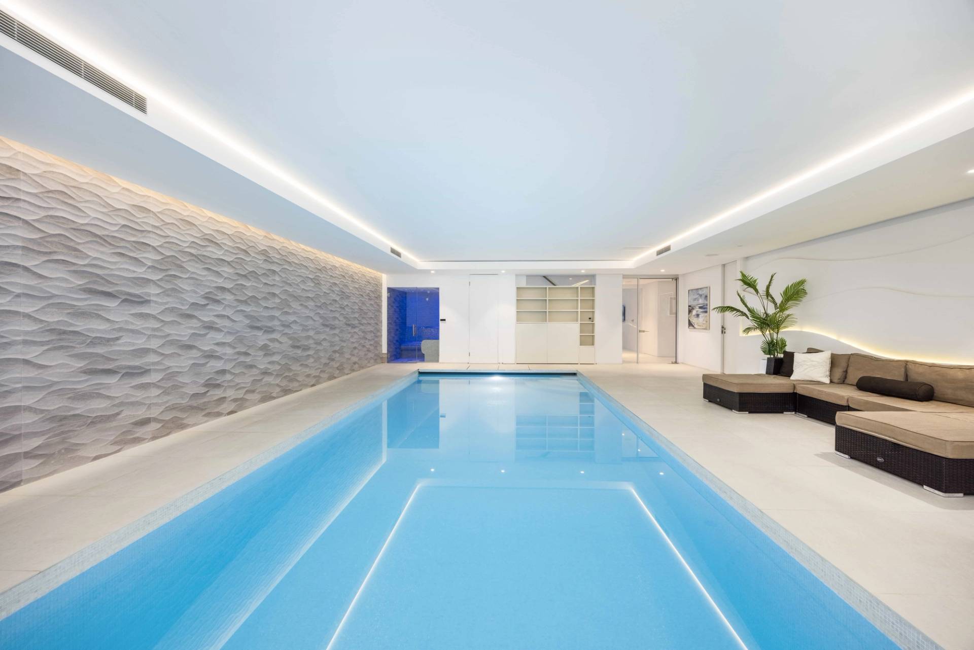 Symmetrical shot of an indoor swimming pool with pristine clear water and white floor tiles, Love Locations WD7.