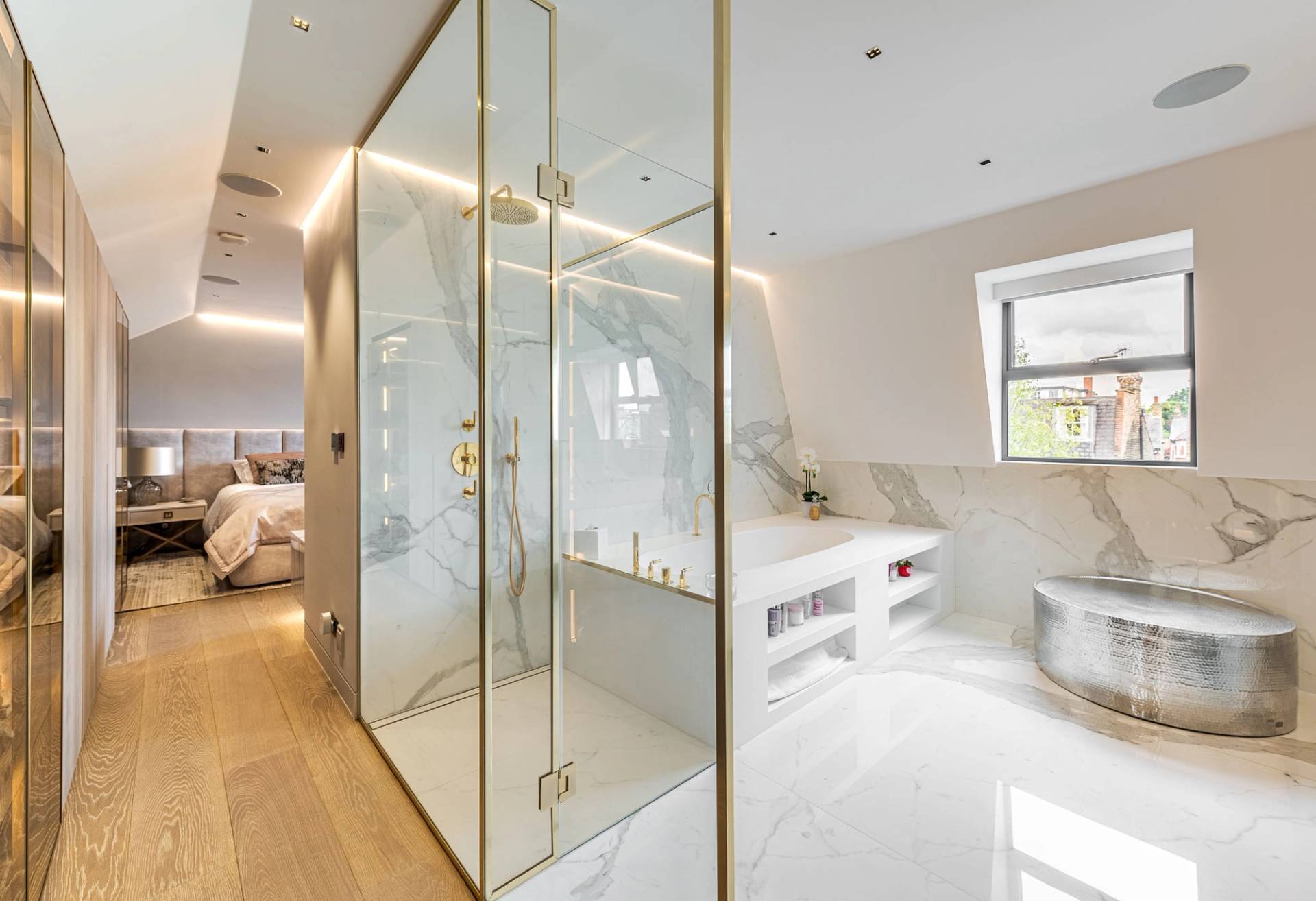 Luxury ensuite shower room featuring a glass enclosure with gold brass framing and marble tiles, Love Locations SW11.
