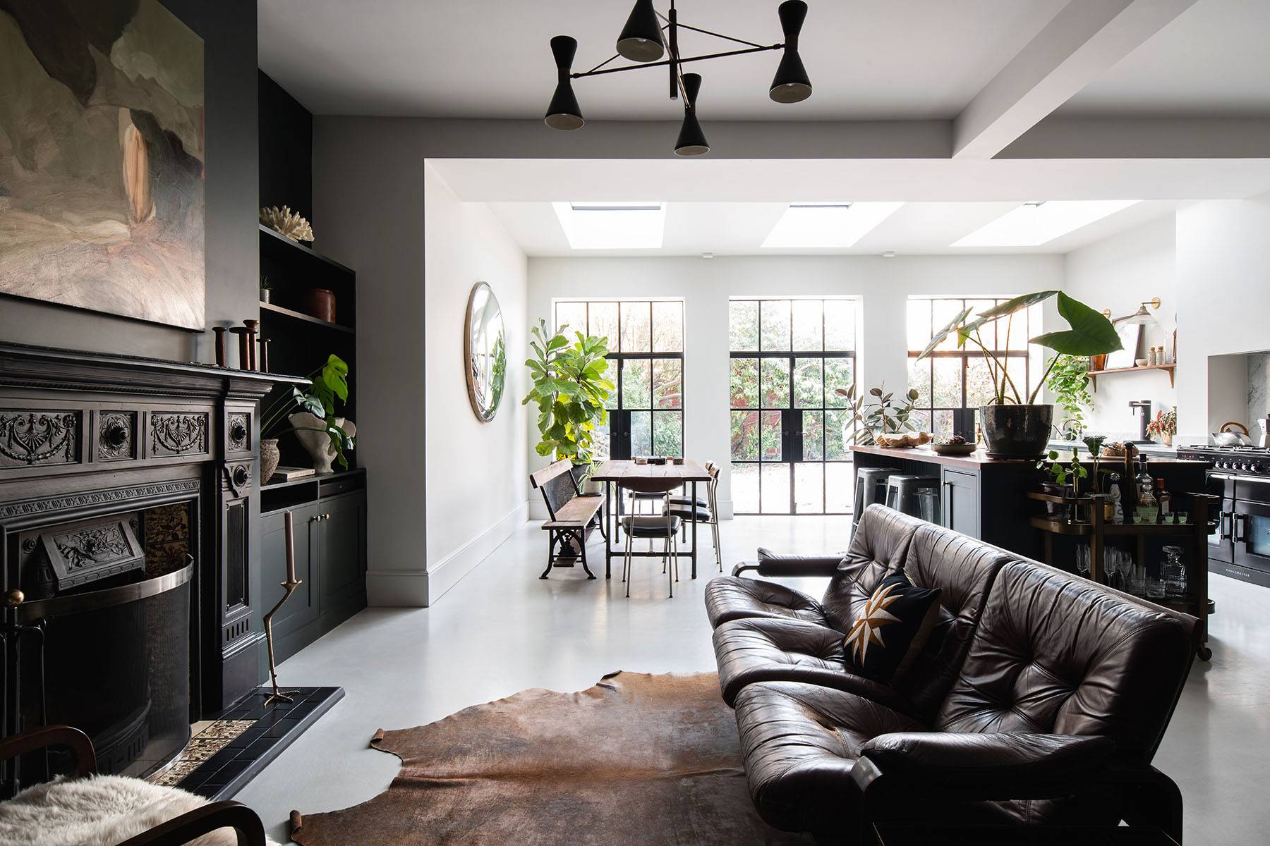 Industrial open-plan kitchen shoot location in Streatham, SW16 featuring dark green island, polished concrete floors, and black leather sofa via Love Locations.