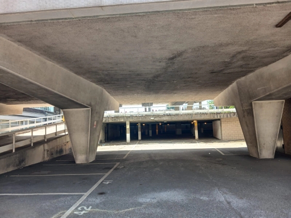 Raw concrete underpass and car park structure for edgy fashion photoshoots in Watford WD18 by Love Locations, featuring heavy brutalist pillars and dramatic shadows.