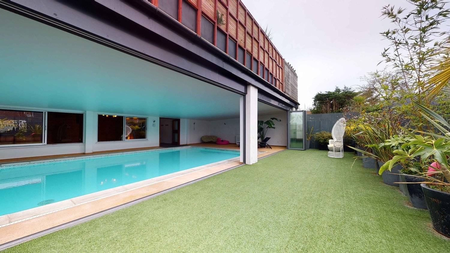 Heated indoor pool room with sliding glass doors opening onto a outdoor artificial lawn garden terrace, Love Locations SW16.