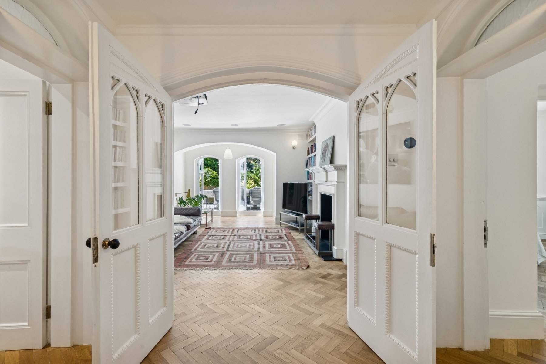 Double doorway transition into a bright living space in a gothic revival Hampstead property via Love Locations.