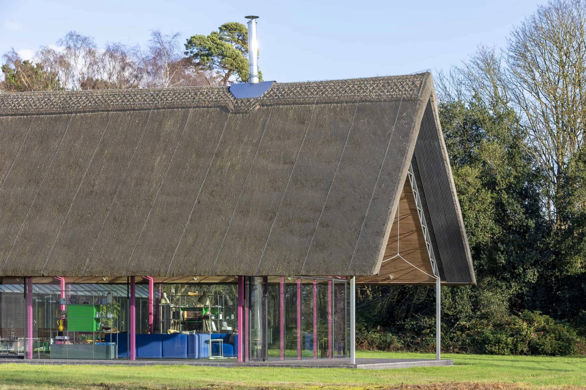 Pitched thatched roof building framed by full-height glass walls and green lawn grounds in Saxmundham, Love Locations IP17.