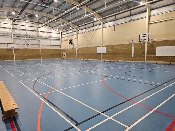Huge school gymnasium filming location featuring a modern blue court surface and high-intensity industrial lighting, Love Locations HP13.