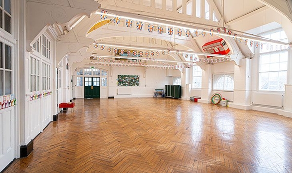Bright and airy historic school hall with open rafters and natural light, premium institutional location by Love Locations.