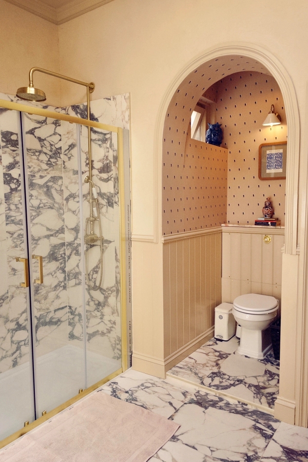 Eclectic bathroom suite showing a walk-in glass shower with ornate blue-and-white patterned tiles next to a traditional toilet and basin, Love Locations.