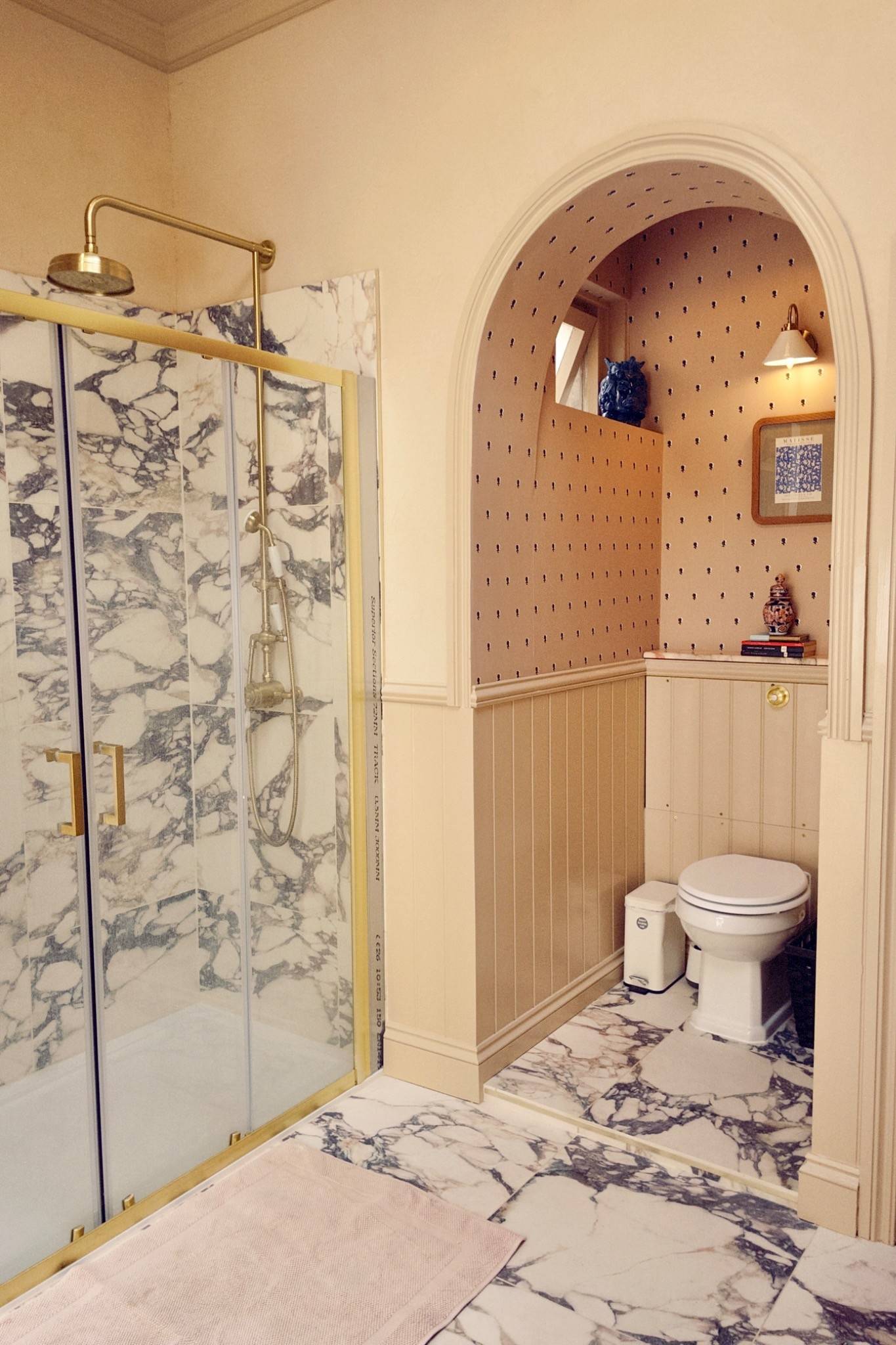 Eclectic bathroom suite showing a walk-in glass shower with ornate blue-and-white patterned tiles next to a traditional toilet and basin, Love Locations.
