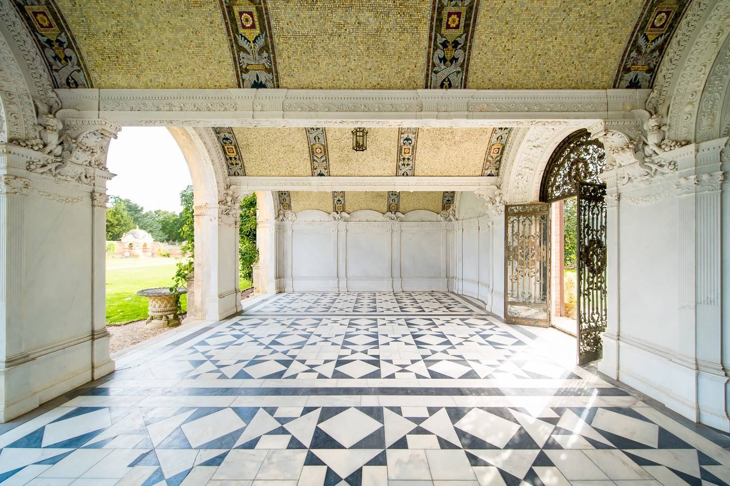 Classical loggia pavilion with geometric marble tile floor and carved stone arches in Hertfordshire AL9 by Love Locations.