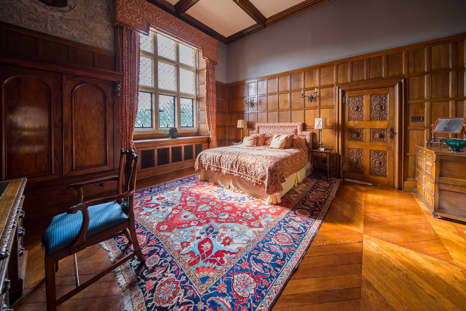Traditional country estate bedroom location house in Hertfordshire AL9 through Love Locations, featuring heavy drapes, Persian rug, and dark wood furniture.