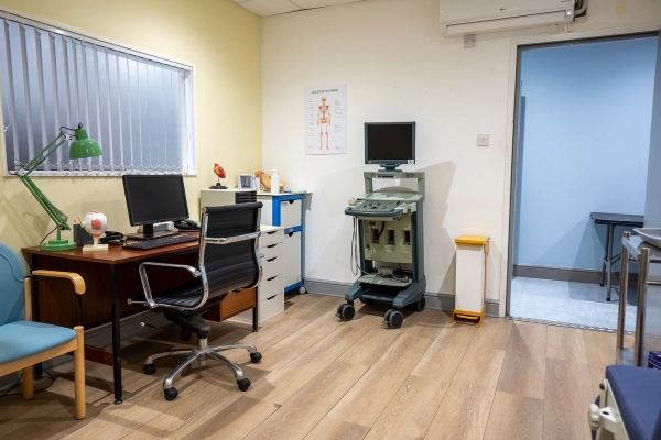 Doctor consultation room with desk, medical equipment, and privacy window blinds, Love Locations UB4.