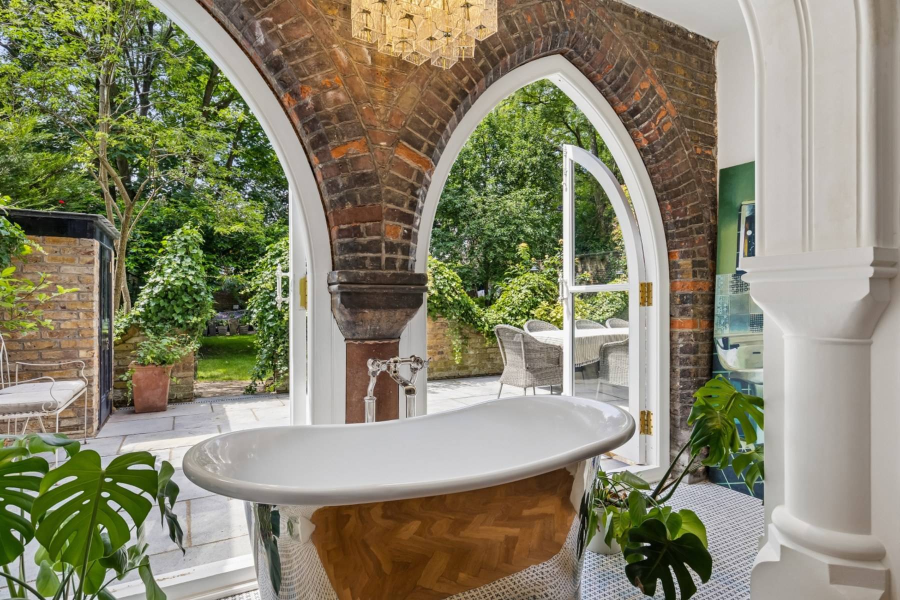 Close-up detail of a copper slipper tub and gothic arched brick doorway in Hampstead London via Love Locations.