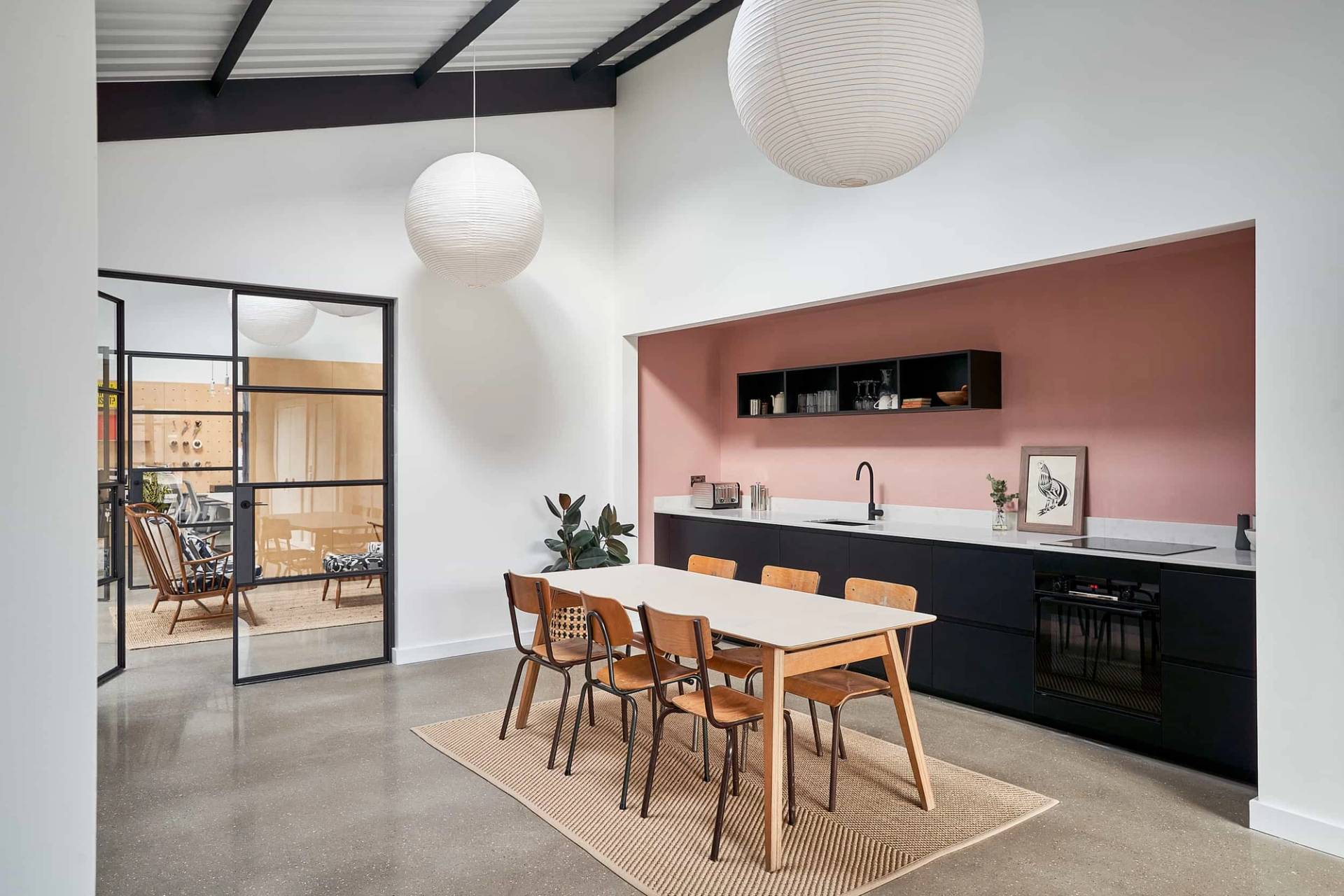 Terracotta pink dining alcove with built-in bench, wooden dining table, and paper globe pendant light, Love Locations IP30.