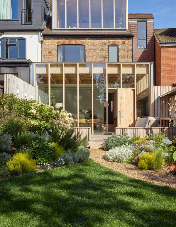 Rear architectural extension of a 1930s house featuring vertical timber post framing and curved garden lawn, Love Locations E17.