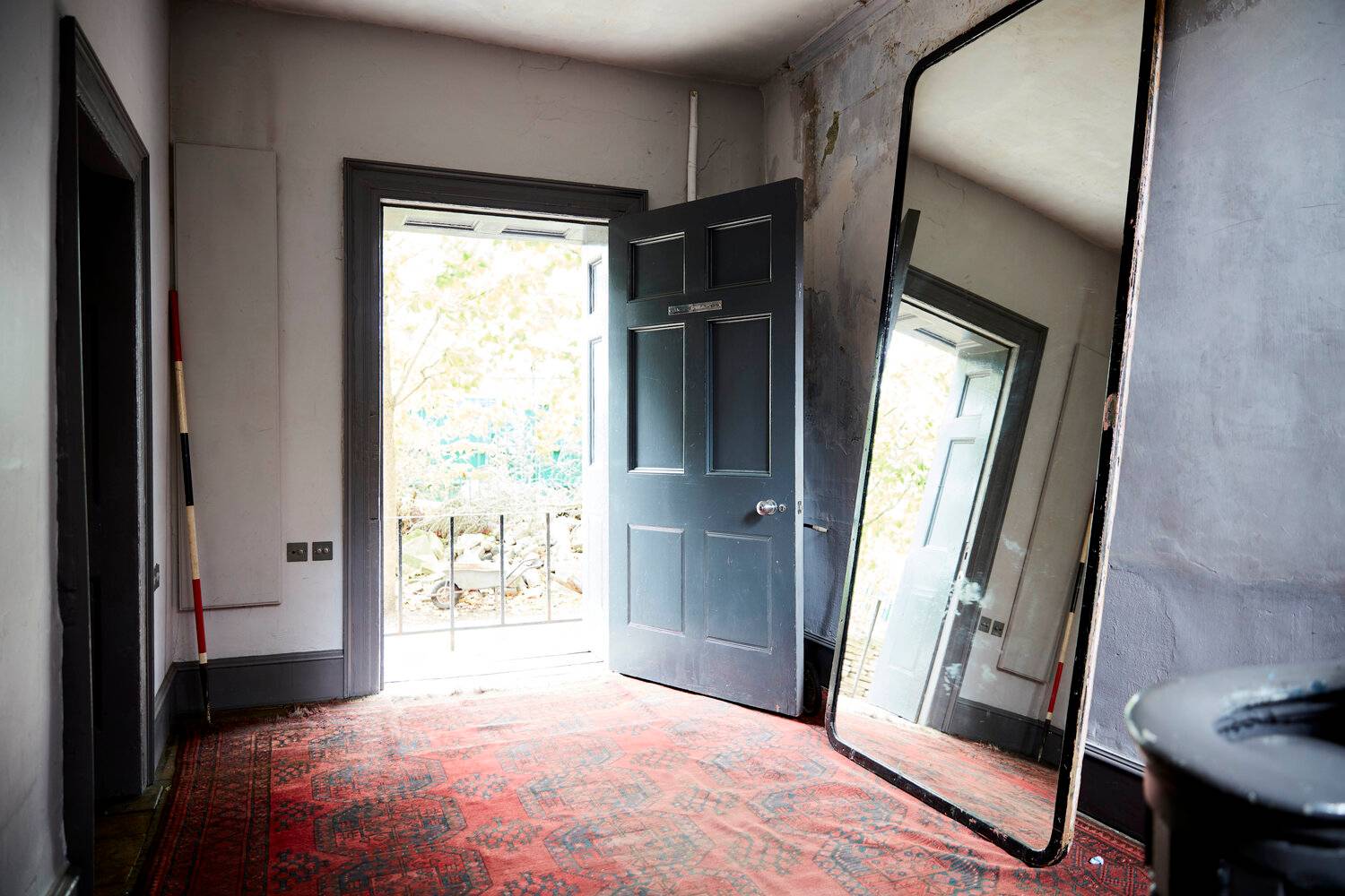 Open Georgian entrance doorway looking onto a red carpet hallway and leaning full-length mirror, Love Locations.