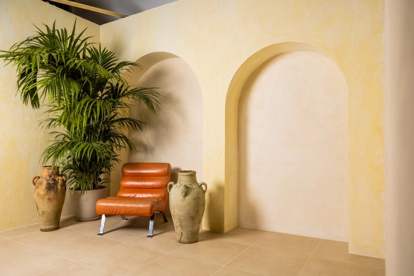 Creative photography studio set in Tottenham, N15 featuring plaster Mediterranean wall arches, terracotta leather lounge chair, and stone amphora urn via Love Locations.