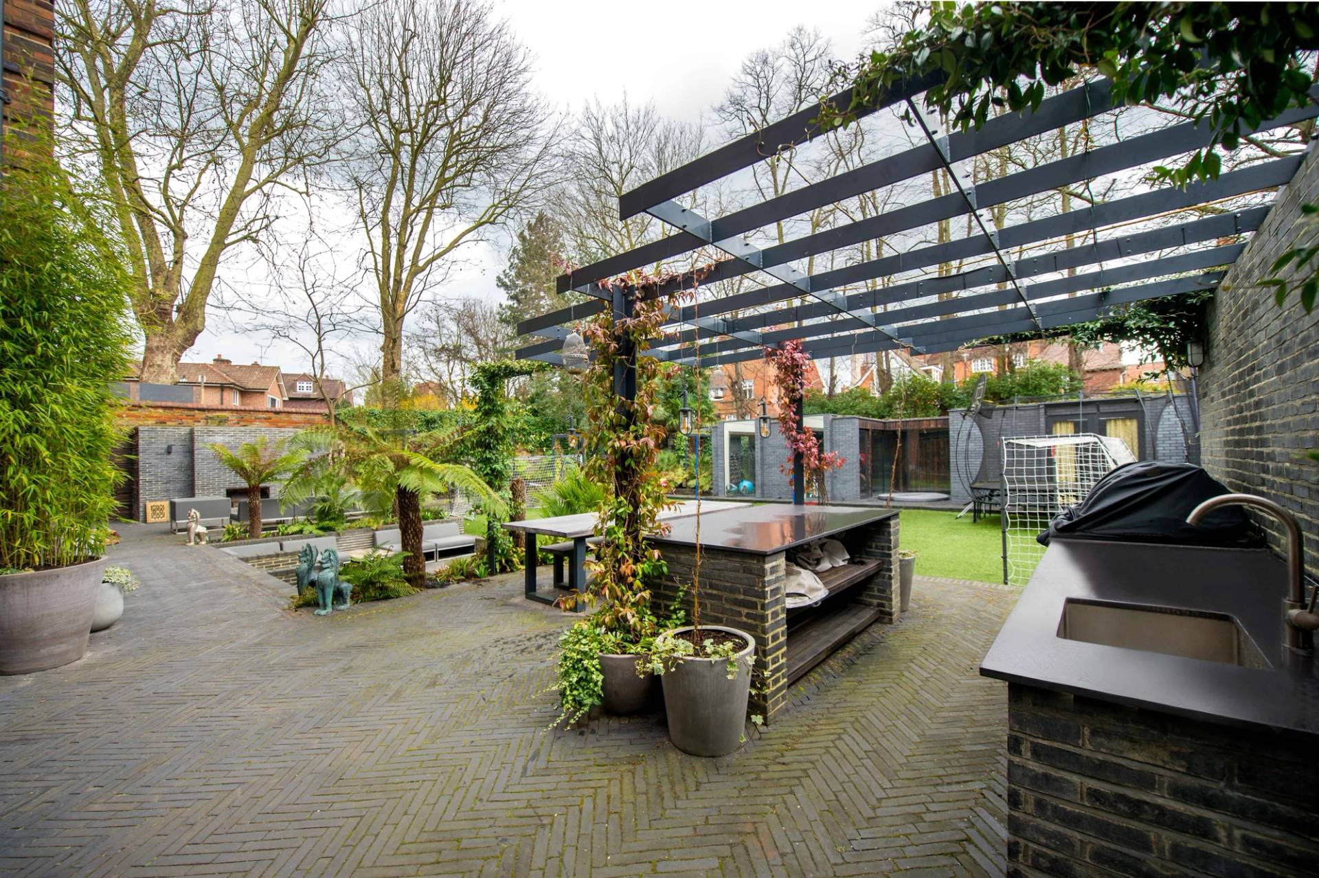 Covered outdoor kitchen and patio pergola structure surrounded by mature greenery, ideal for summer lifestyle advertising, Love Locations.