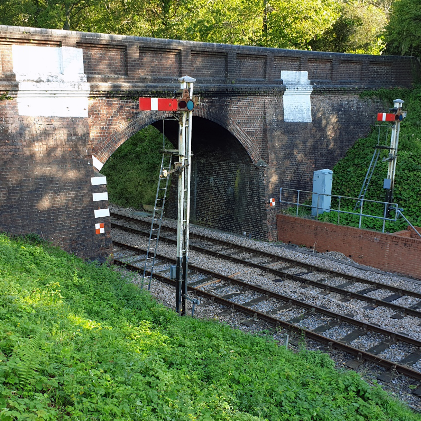 Traditional railway signal post and brick bridge over double tracks in Sheffield Park, Sussex, Love Locations.