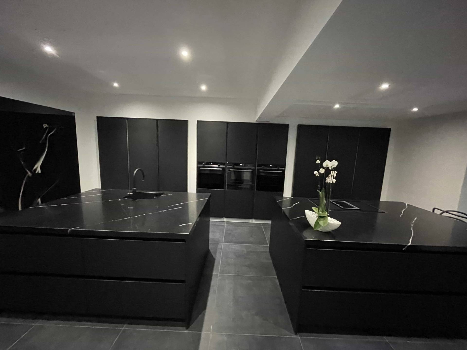 Sleek matte black kitchen with twin marble islands and recessed spot lighting in Loughton, IG10, perfect for culinary TV ads and appliance marketing, Love Locations.