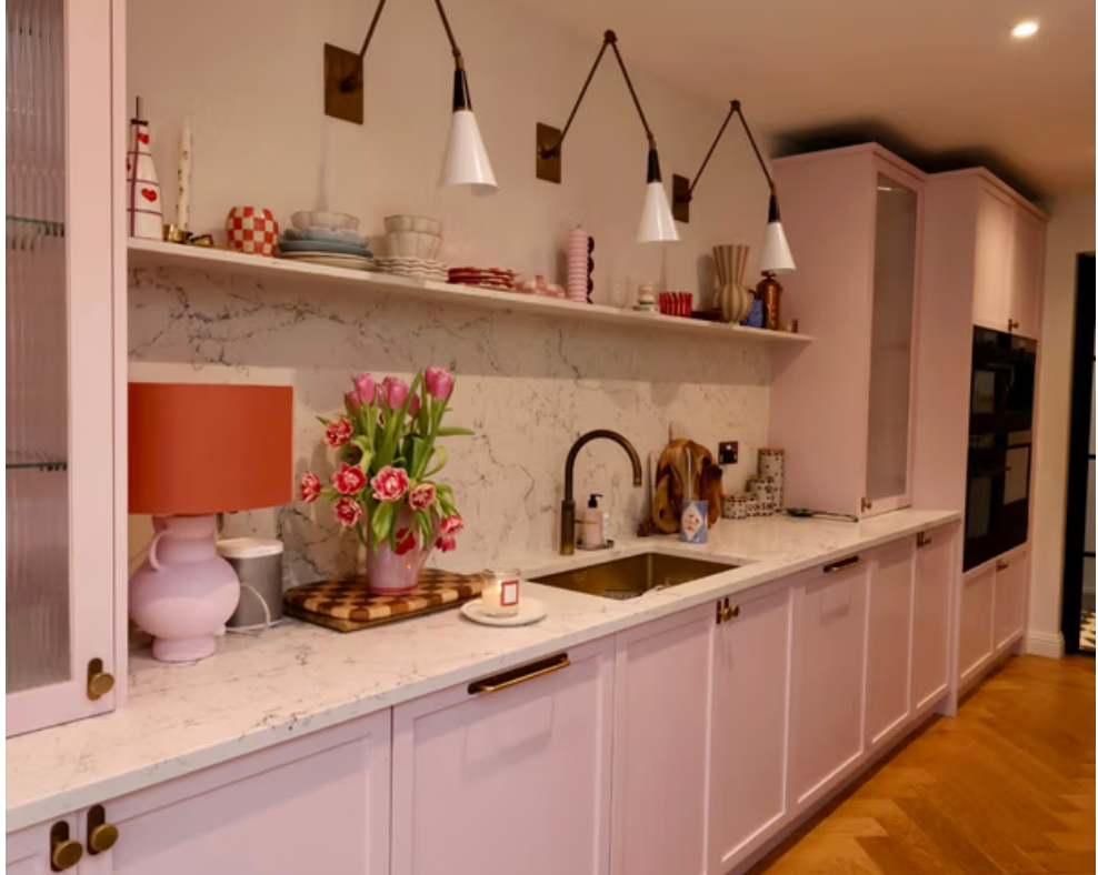 Pastel pink kitchen at Cassio featuring shaker cabinetry, marble worktops, brass handles and soft pink styling accessories.