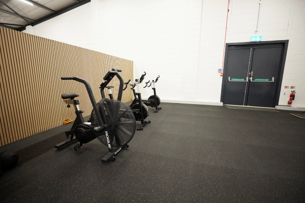 Row of professional air bikes positioned neatly against a stylish slatted wooden wall in a Winchester fitness studio, Love Locations.