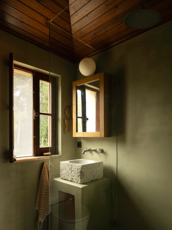Sage green microcement bathroom featuring a carved stone vessel sink and timber window frame, Love Locations 2705-064.