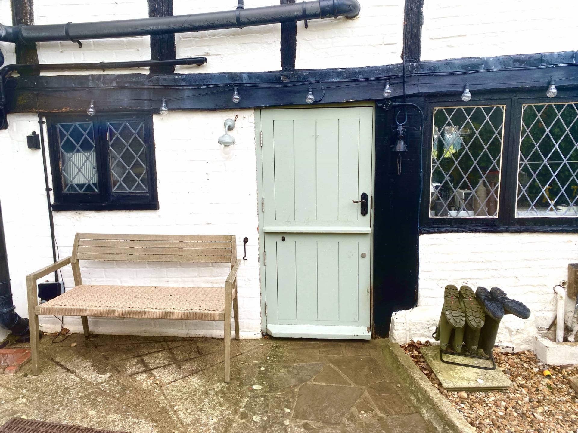 Rear cottage doorway and patio seating area surrounded by historic timber beams and outdoor country gear, perfect for rustic lifestyle brand shoots, Love Locations.