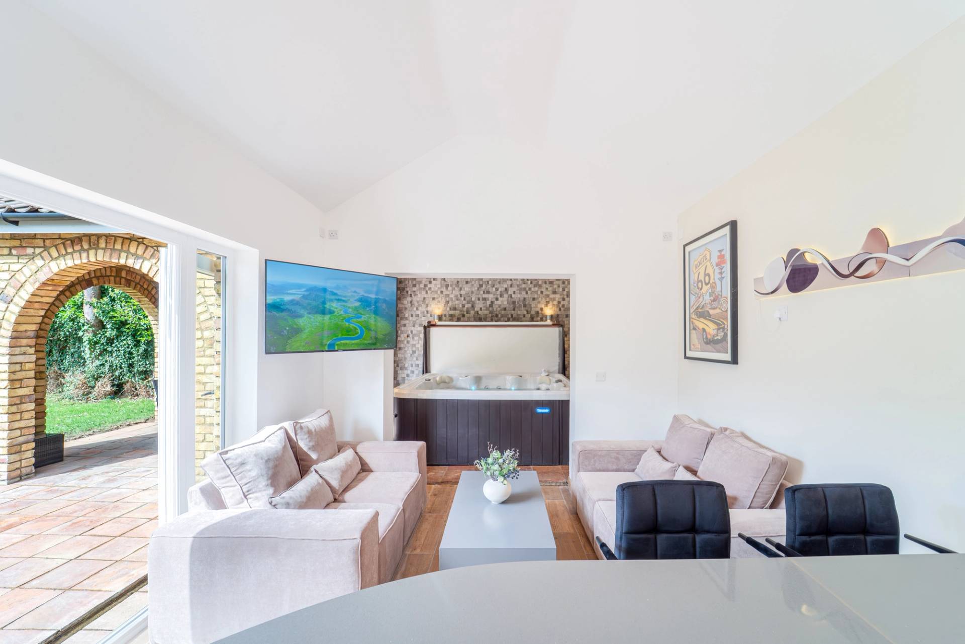 Light-filled sitting room transition with plush sofas, TV wall, and white ceiling coving, Love Locations RM11.