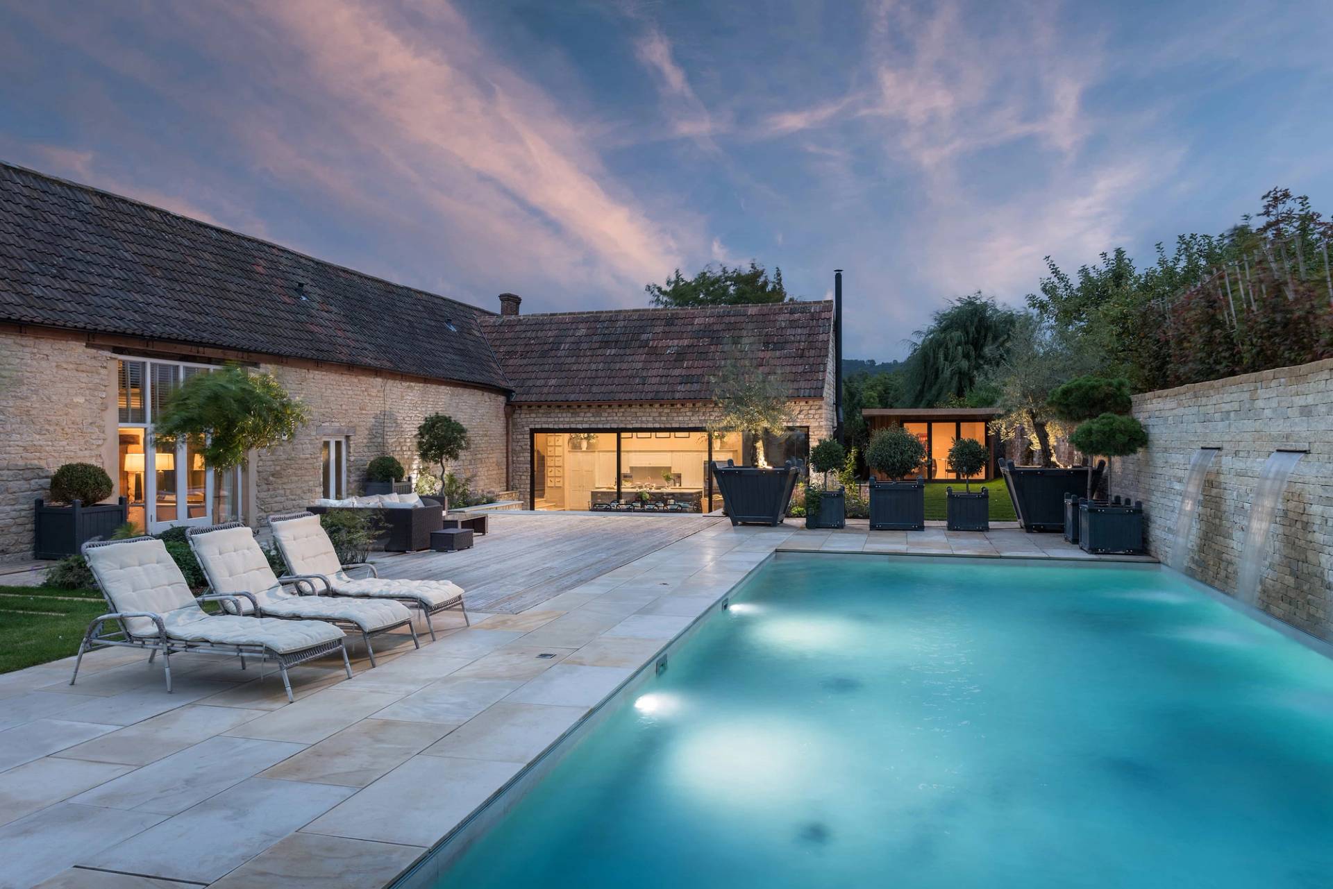 Dusk illuminated swimming pool and outdoor lounge lighting setup on a private estate in Cheltenham GL51 via Love Locations.