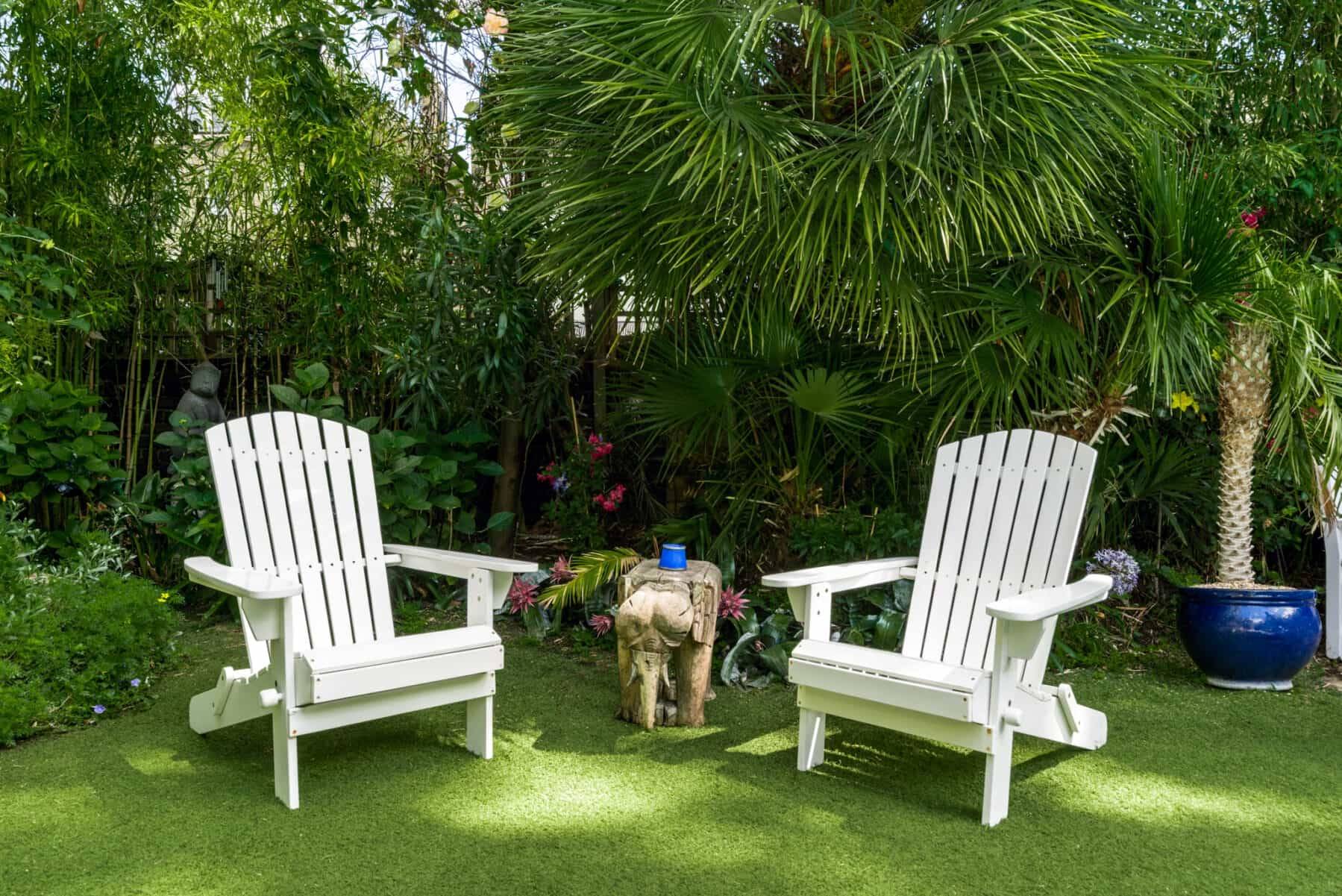 White Adirondack garden chairs set on manicured lawns surrounded by exotic palm trees in a Kensington and Chelsea location home, Love Locations.