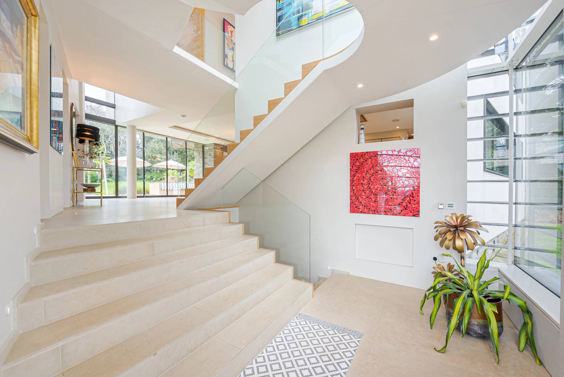 Wide-angle view of a floating timber staircase set in a double-height glass-fronted entrance hallway, Love Locations KT2.
