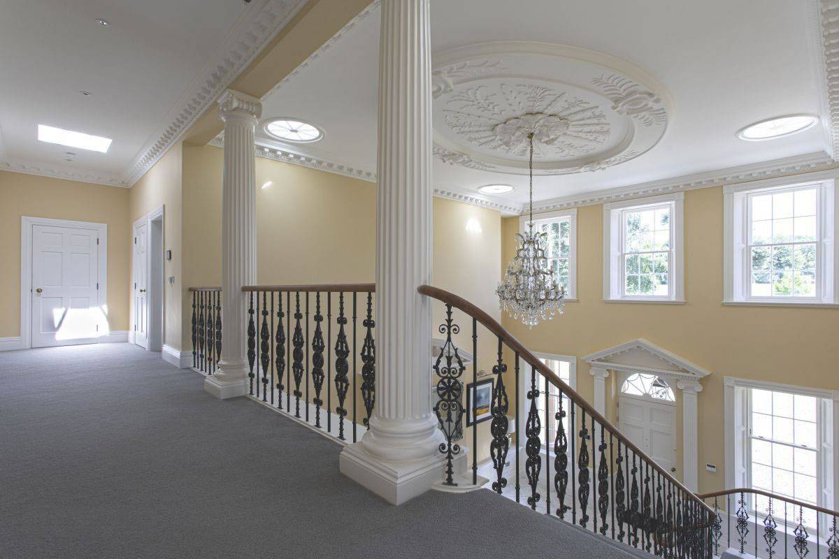 Stately first-floor landing featuring classical columns, ornate ceiling roses, and overlooking the grand hall, Love Locations property in Haywards Heath.