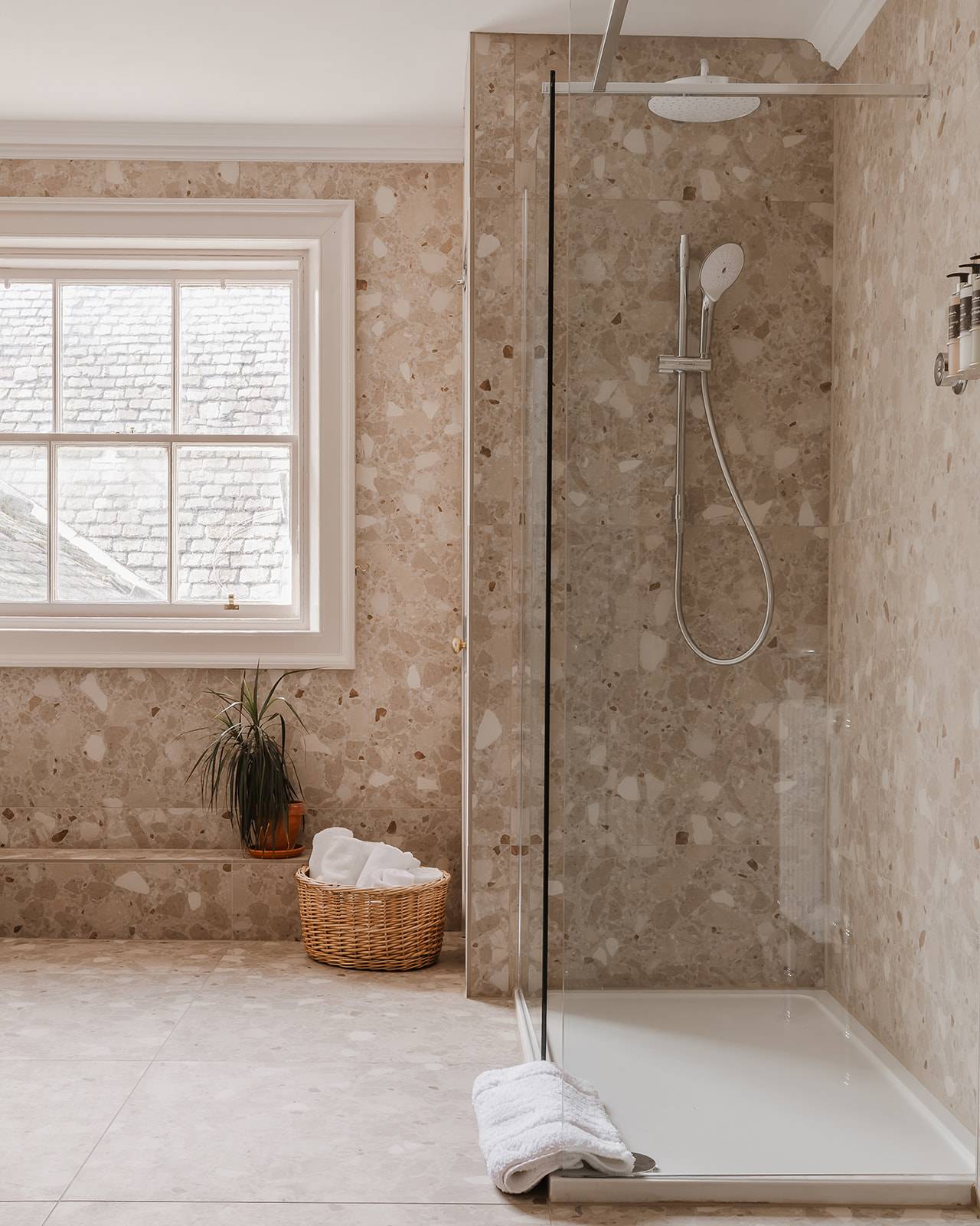 Walk-in shower enclosure wrapped in textured marble wall tiles, Love Locations KY15.