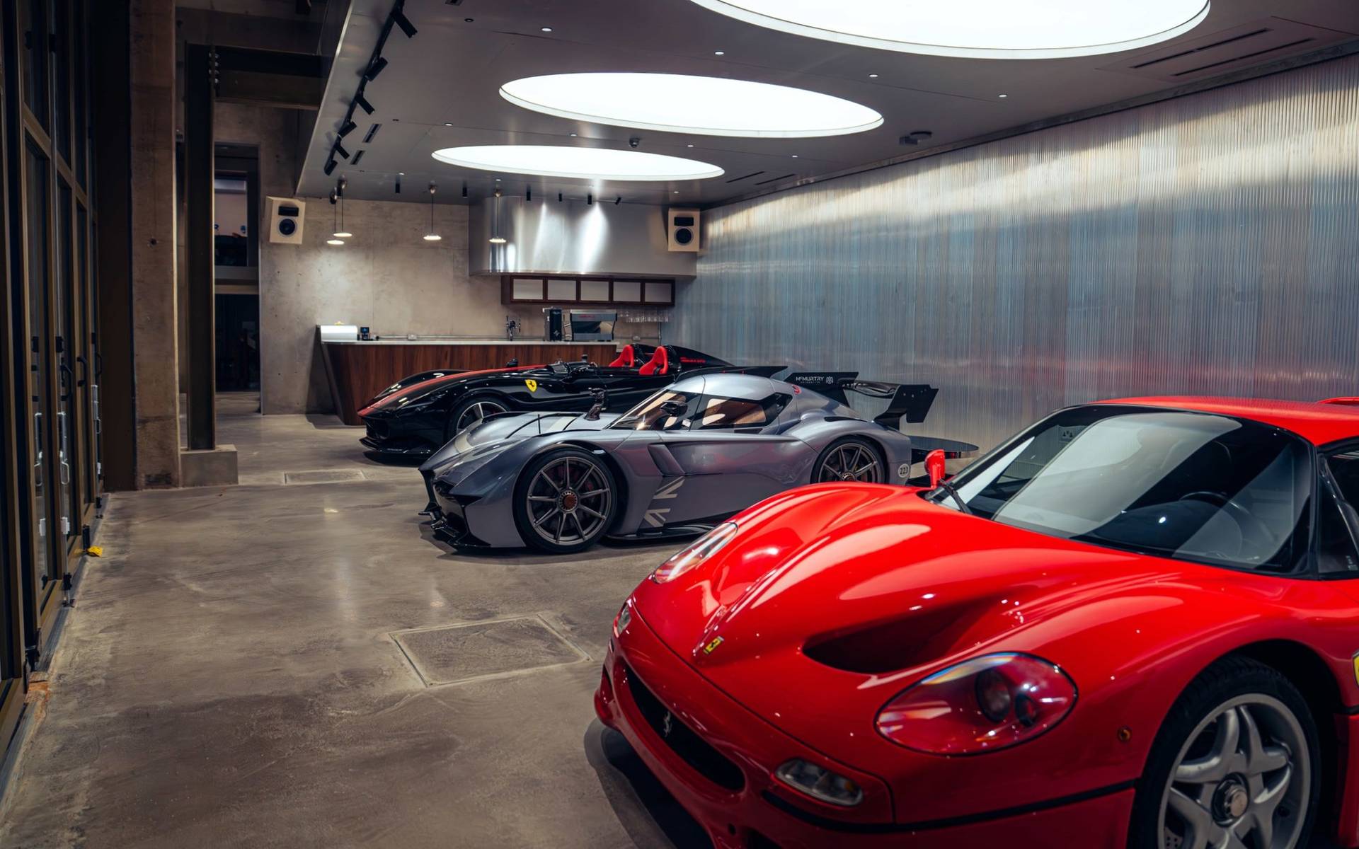 Sleek modern venue space housing luxury supercars including a red Ferrari and silver sports car through Love Locations.