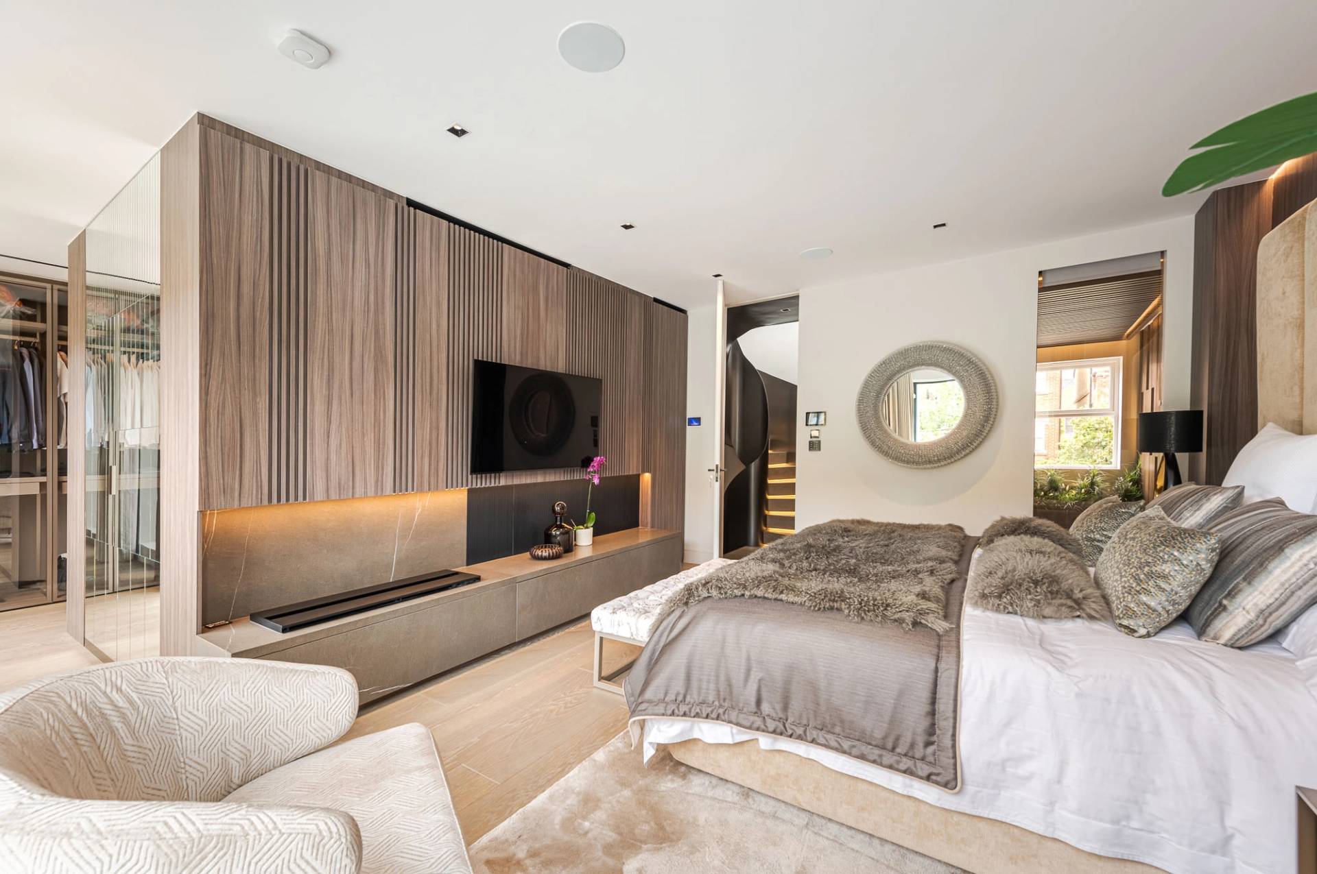 Bedroom suite view looking towards a wall-mounted TV, built-in wooden storage, and ensuite entrance, Love Locations SW11.