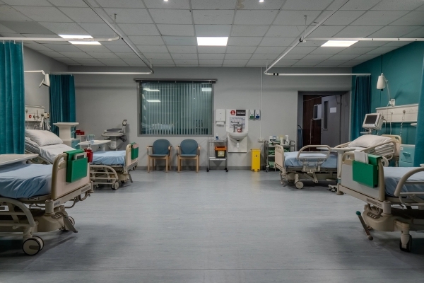 Hospital ward room set with multiple patient beds, privacy curtains, and wall-mounted monitors, Love Locations UB4.