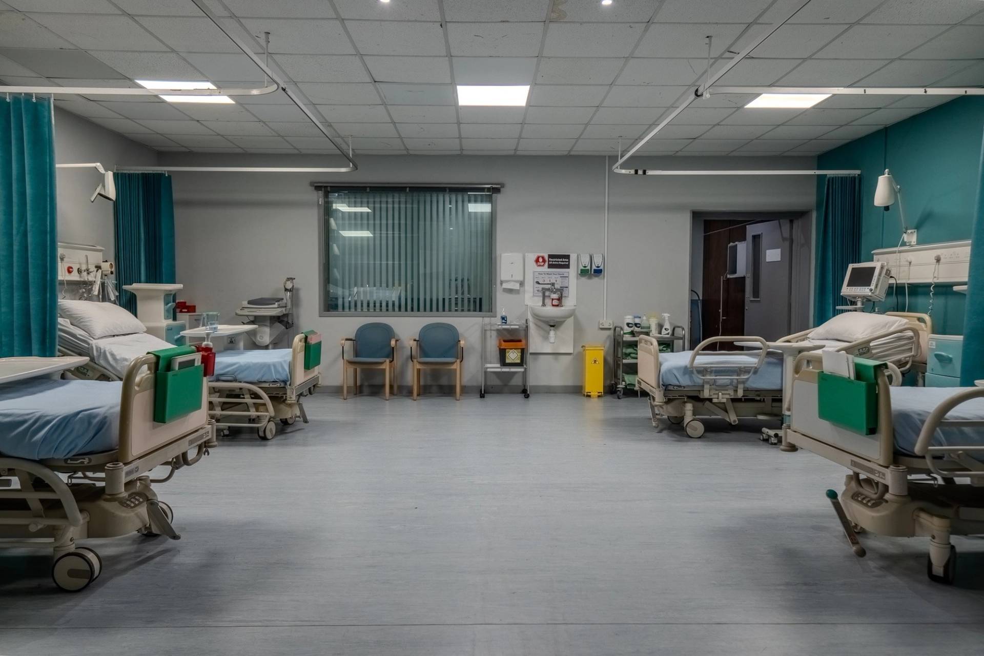 Hospital ward room set with multiple patient beds, privacy curtains, and wall-mounted monitors, Love Locations UB4.