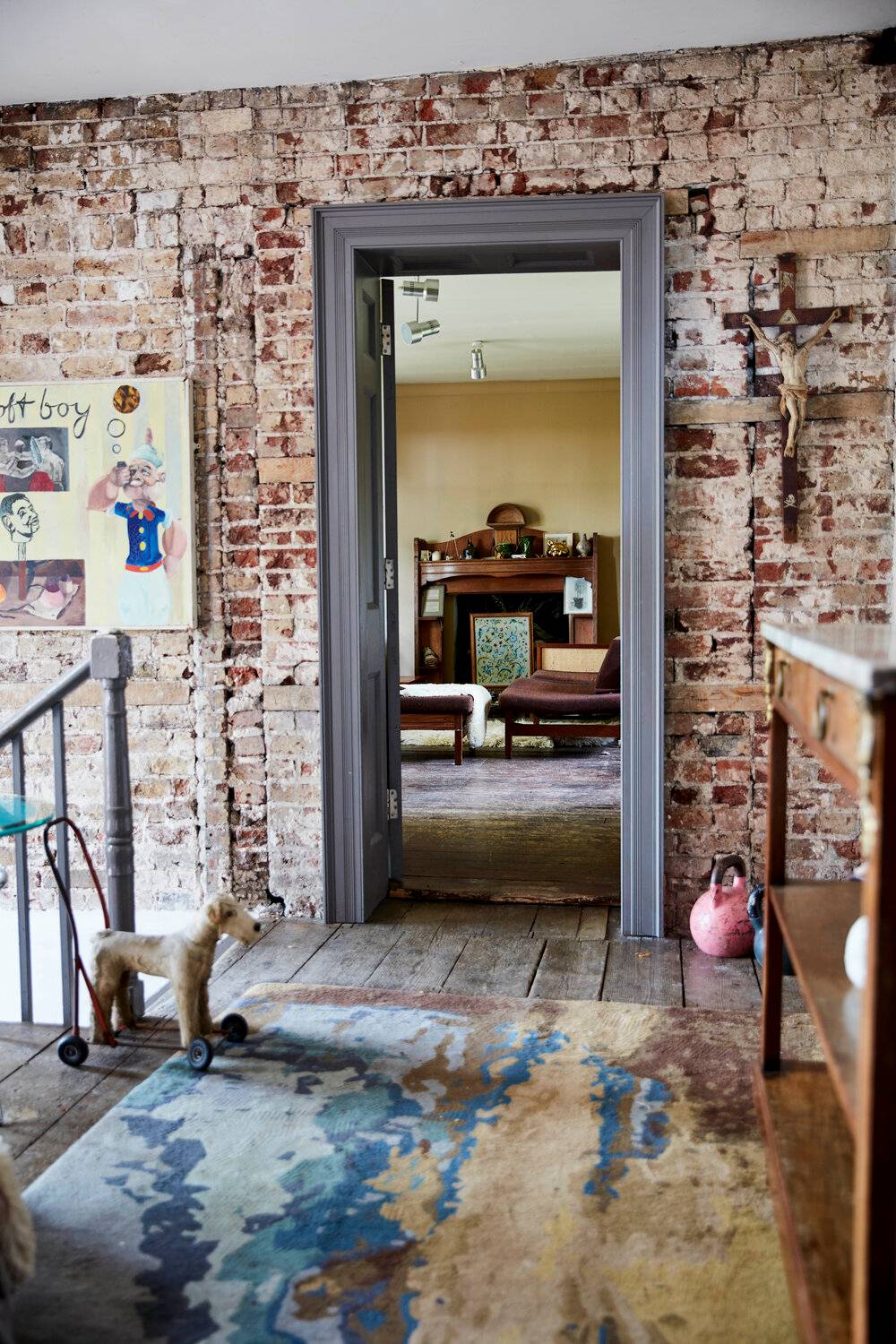 Exposed brick doorway looking into a distressed living room with a marble fireplace hearth, ideal for raw aesthetic brand shoots, Love Locations SE8.