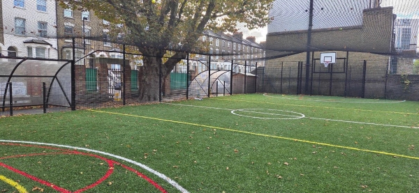Outdoor green astro turf sports pitch and caged playground area at a North London primary school, managed by Love Locations.