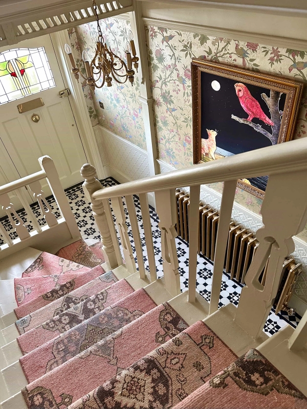 Period wooden staircase with ornate balustrade, pink runner, and cast-iron column radiator, Love Locations N13.